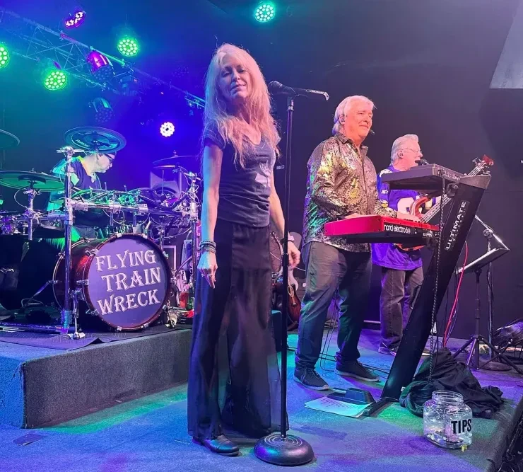 Baibi and Loren on stage – blue and green stage lighting, Flying Train Wreck drum kit visible