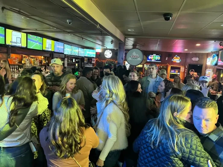 Packed bar crowd at a Flying Train Wreck show – green and yellow lighting