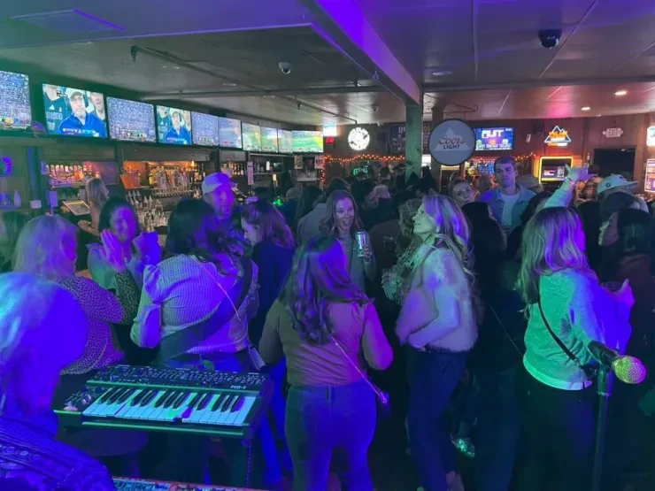 Crowd dancing at a Flying Train Wreck show – green and purple lighting with keyboard visible