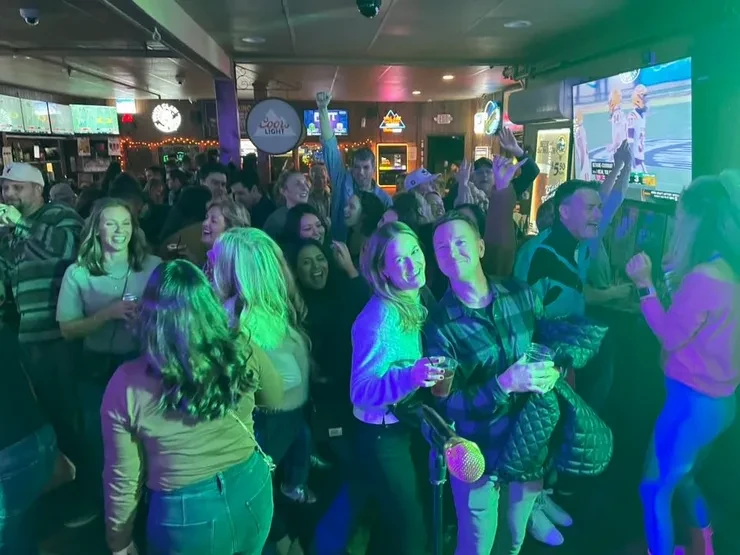 Packed bar crowd dancing under green and purple lights at a Flying Train Wreck show