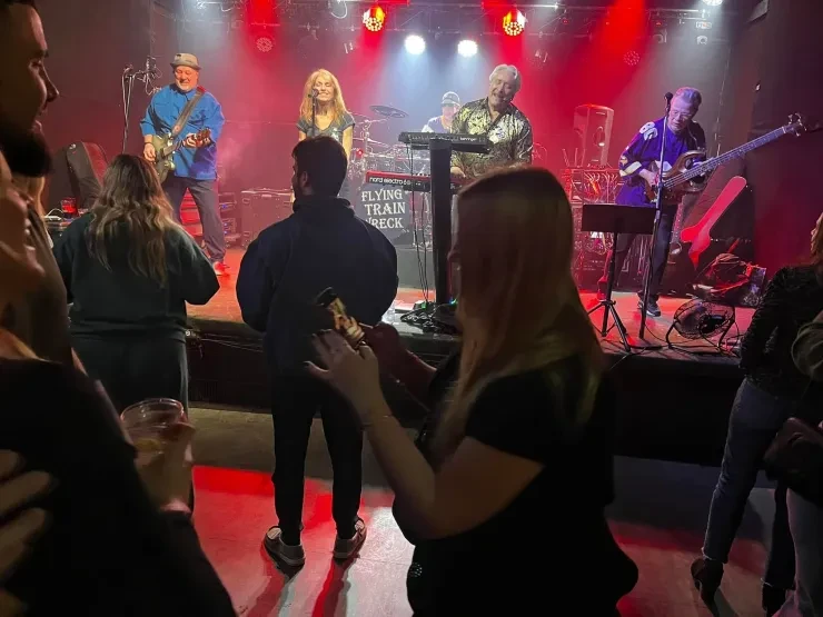 Flying Train Wreck full band performing – red stage lighting with crowd dancing