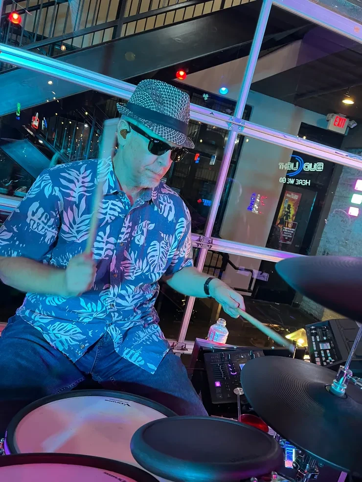 Matt on drums at an indoor venue – blue and purple stage lighting, Bud Light signage
