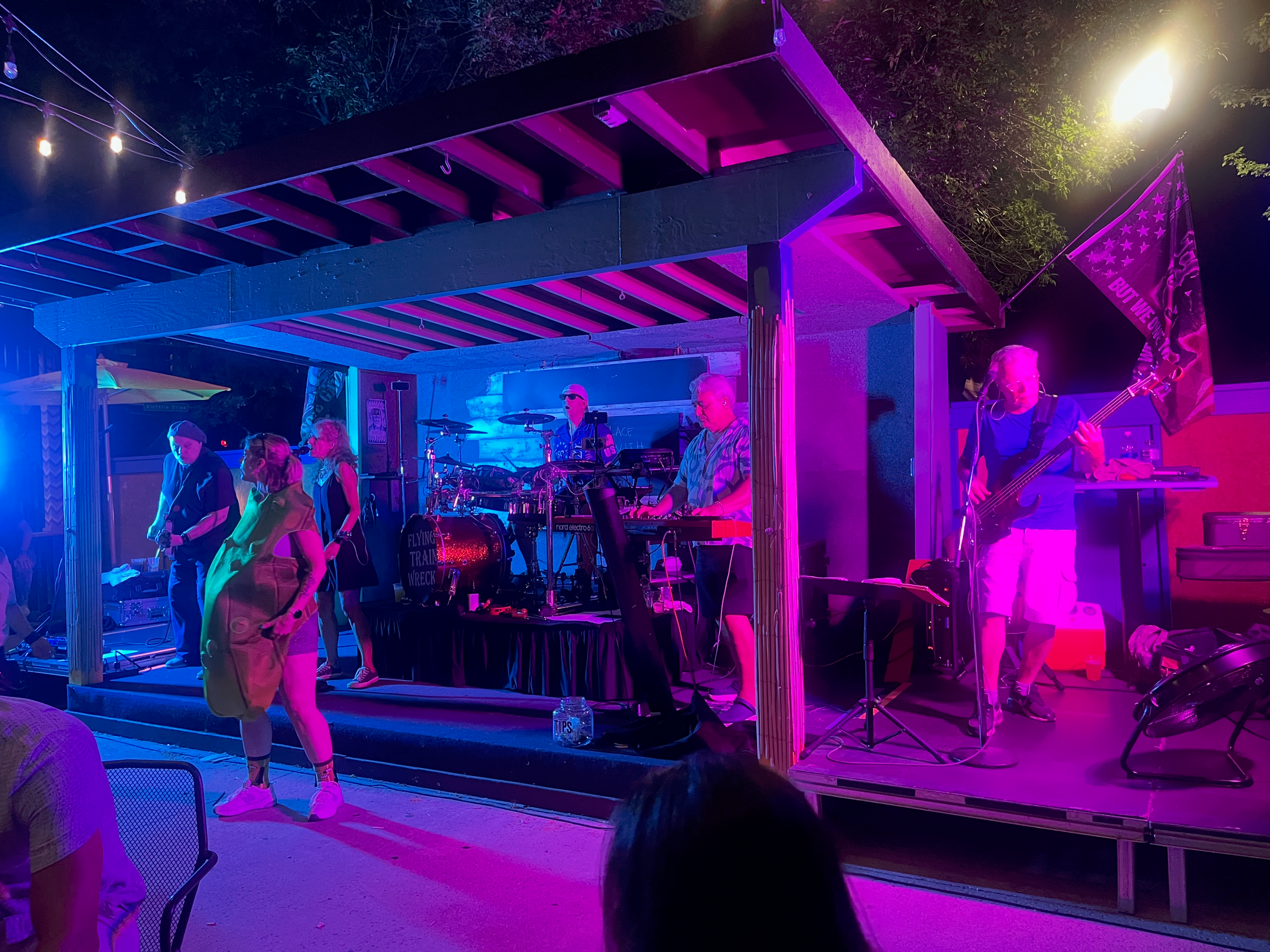 Flying Train Wreck outdoor stage – magenta lighting with bassist