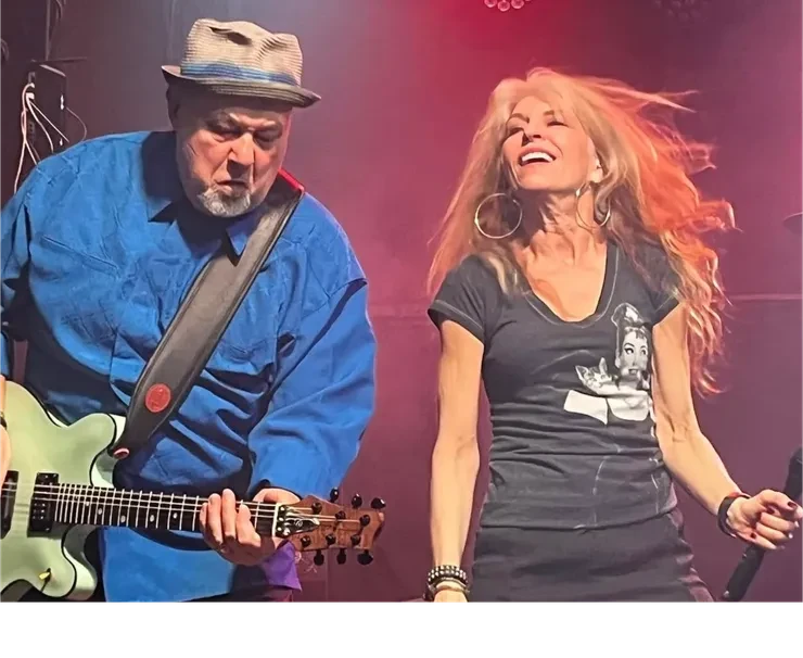 Scot on guitar and Baibi singing – close-up on stage, pink background